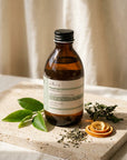 Evera Shampoo No 1 Frequent Use on travertine with green tea leaves and basil sprigs, natural morning light